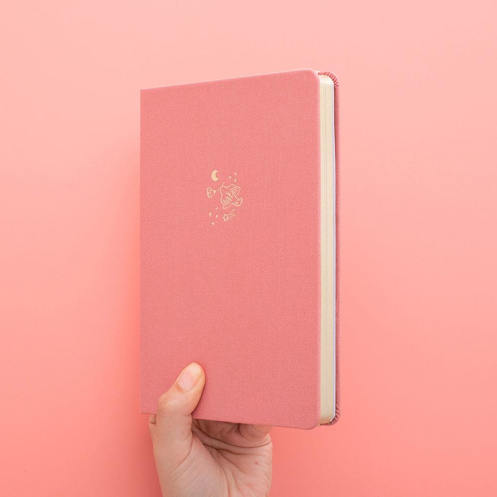 Tsuki ‘Suzume’ Limited Edition Bullet Journal held in hands in coral pink background