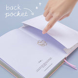 Open back page pocket of Tsuki ‘Lunar Blossom’ Limited Edition Bullet Journal with free bookmark gift held in hands in light blue background