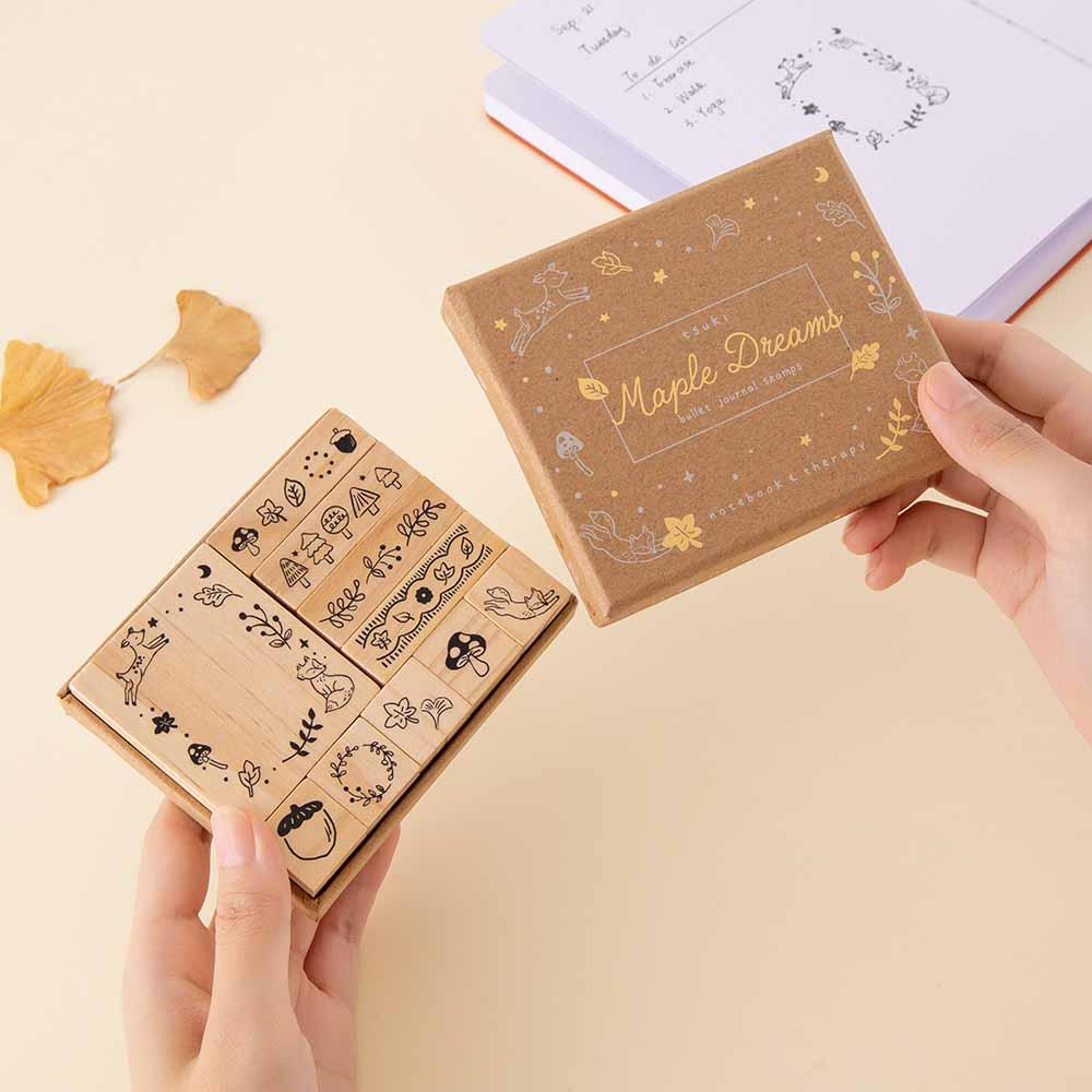 Tsuki ‘Maple Dreams’ Bullet Journal Stamp Set held in hands with autumn leaves and Tsuki ‘Kitsune’ Limited Edition Fox  Bullet Journal  on cream background