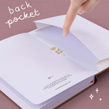 Open Tsuki ‘Vintage Rose’ Limited Edition Bullet Journal with open back page pocket held in hand with free paper clip rose gift on mauve background