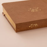 Close up of the gold details on the spine of a brown velvet bullet journal