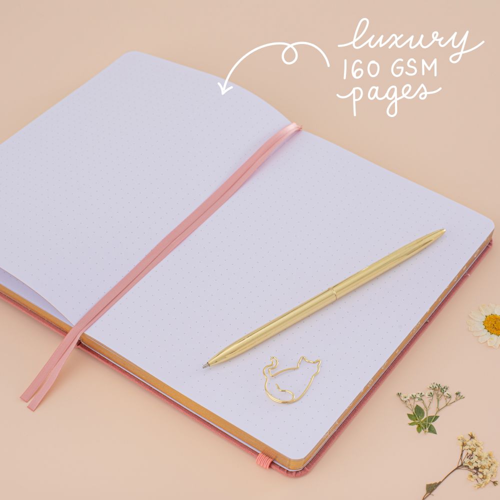 Notebook laid flat on beige background with the words ‘luxury 160gsm pages’ in white lettering