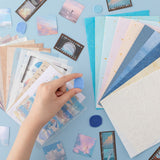 Hand holding a wax seal stamp from the Tsuki ‘Cloud Dreamland’ Scrapbooking Set with paper and stickers spread out in the background