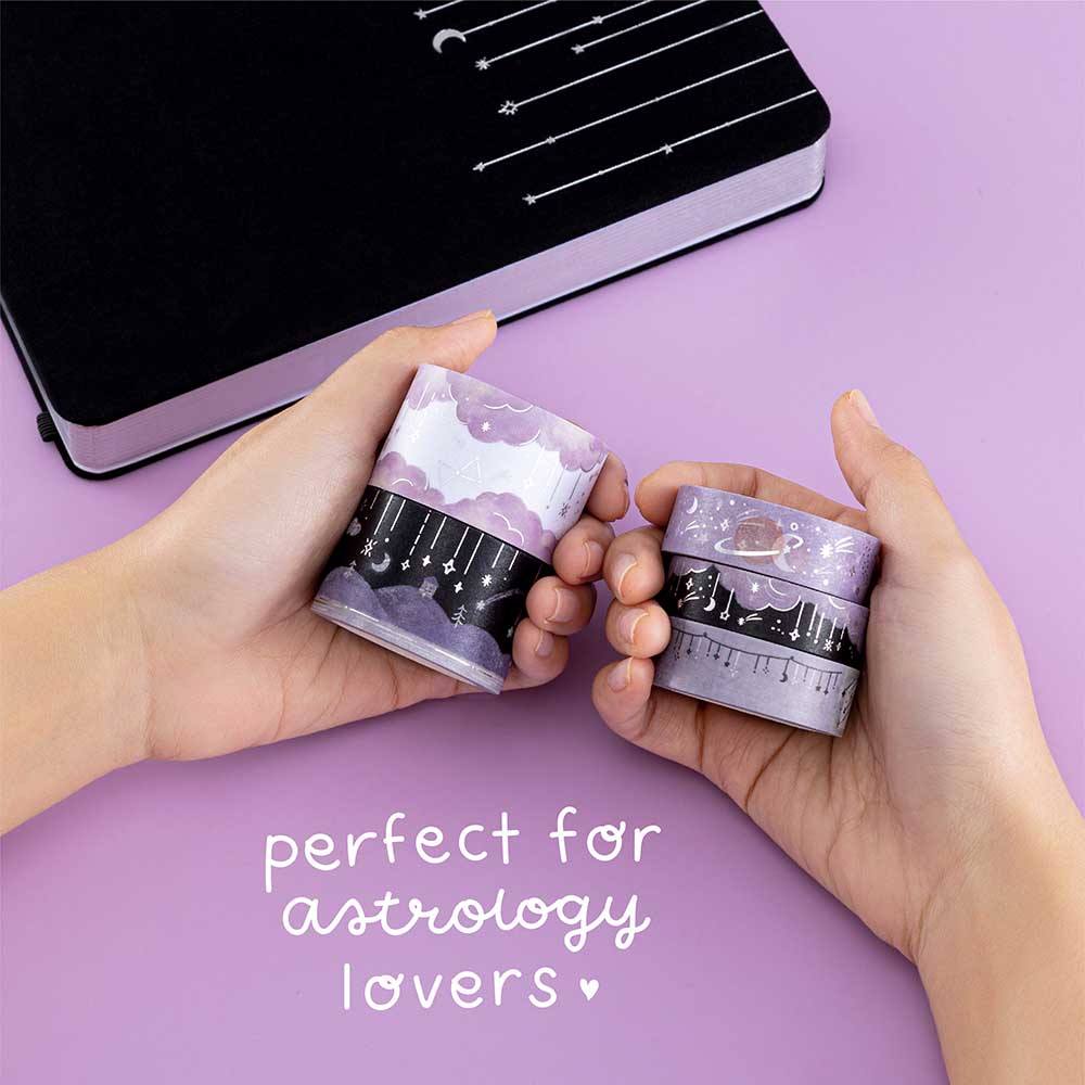 Tsuki ‘Falling Star’ Washi Tape Set perfect for astrology lovers held in hands over Tsuki ‘Falling Stars’ Limited Edition Bullet Journal on purple background