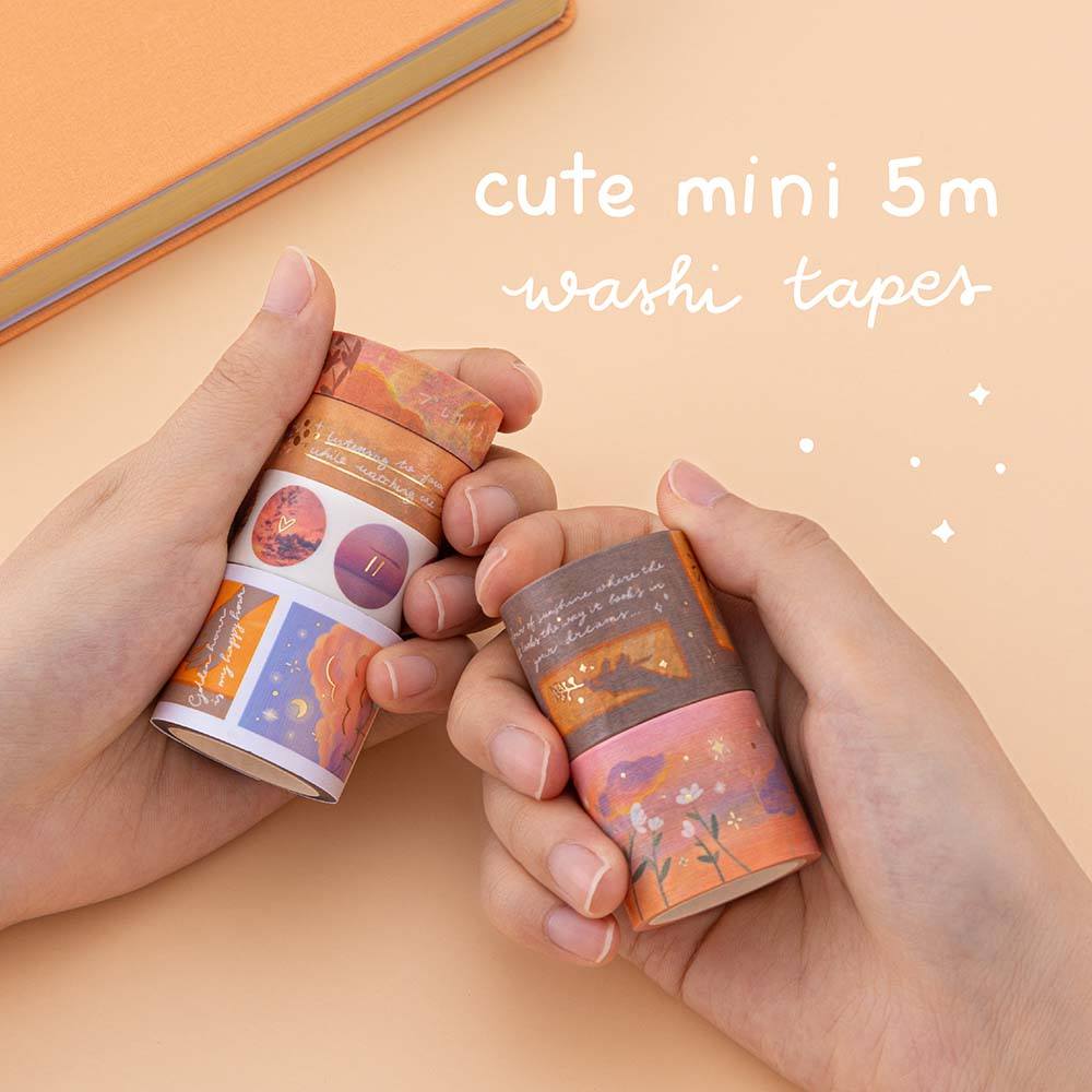Hands holding Tsuki Golden Hour washi tapes on orange background