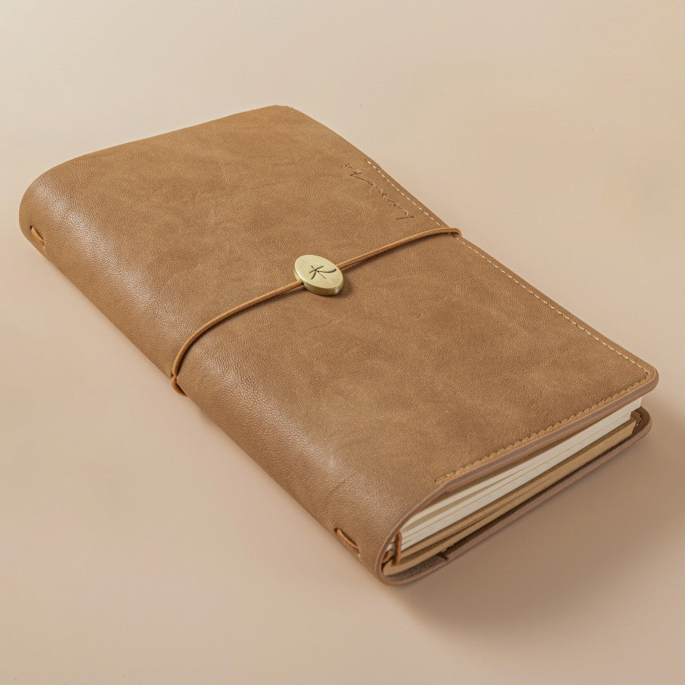 Close up of Hinoki - No.01 Travel Notebook with logo debossing that says Hinoki and a Japanese Hinoki symbol on a gold metal charm