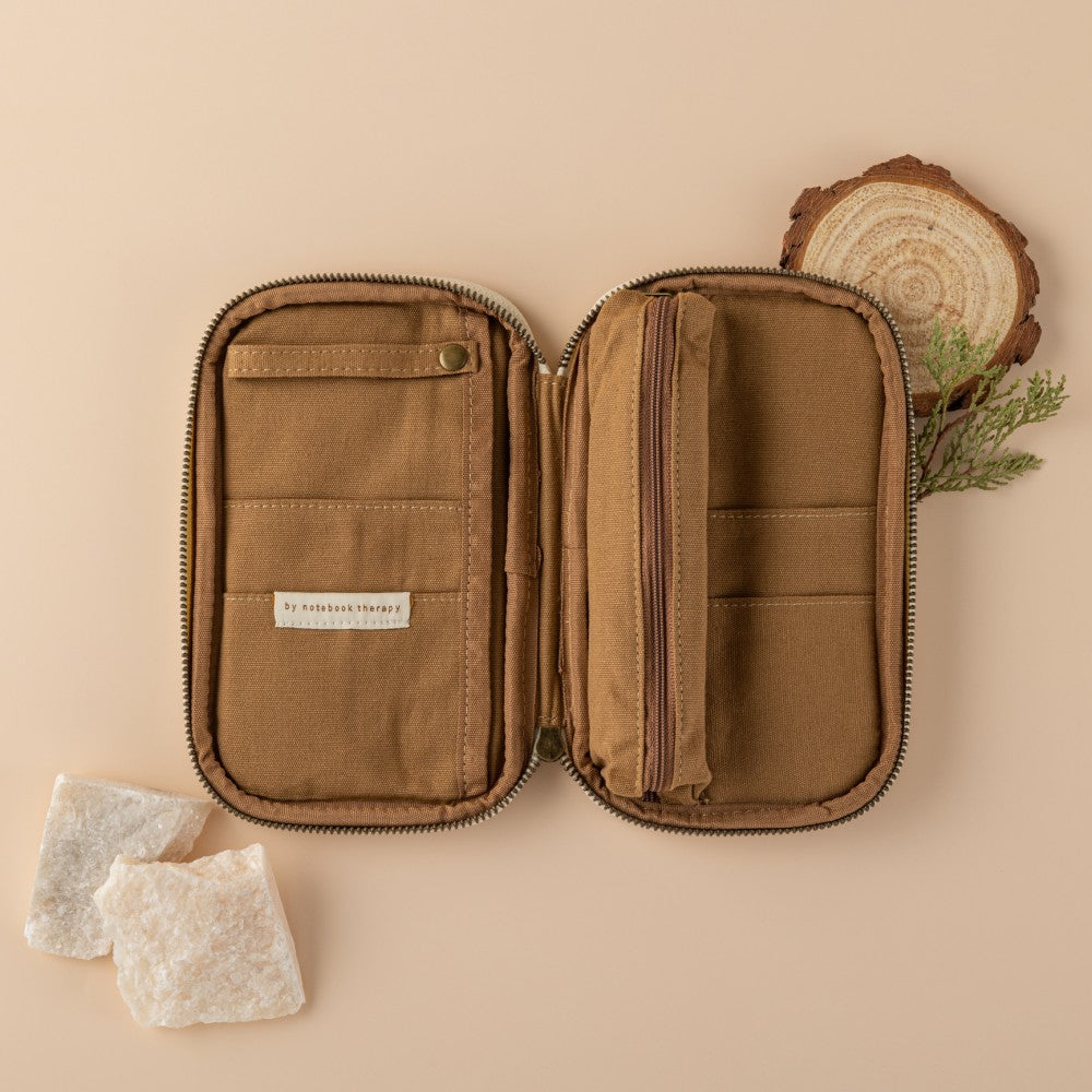 Empty opened brown pencil case with 4 pockets, a strap for pens and a pencil case compartment in the middle