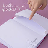 Finger lifting up the back pocket of a bullet journal
