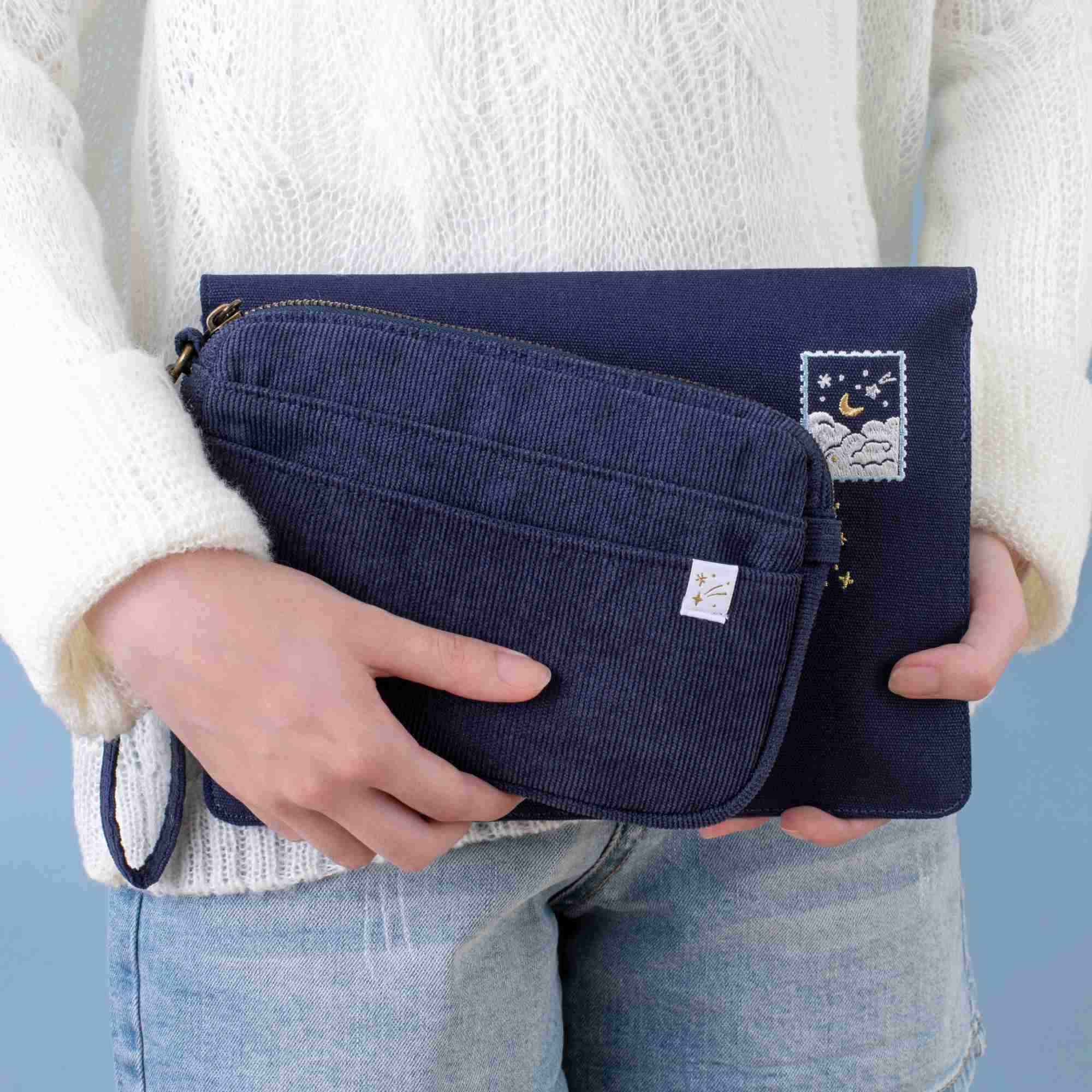 Model holding both Cloud Dreamland travel pouch and notebook pouch