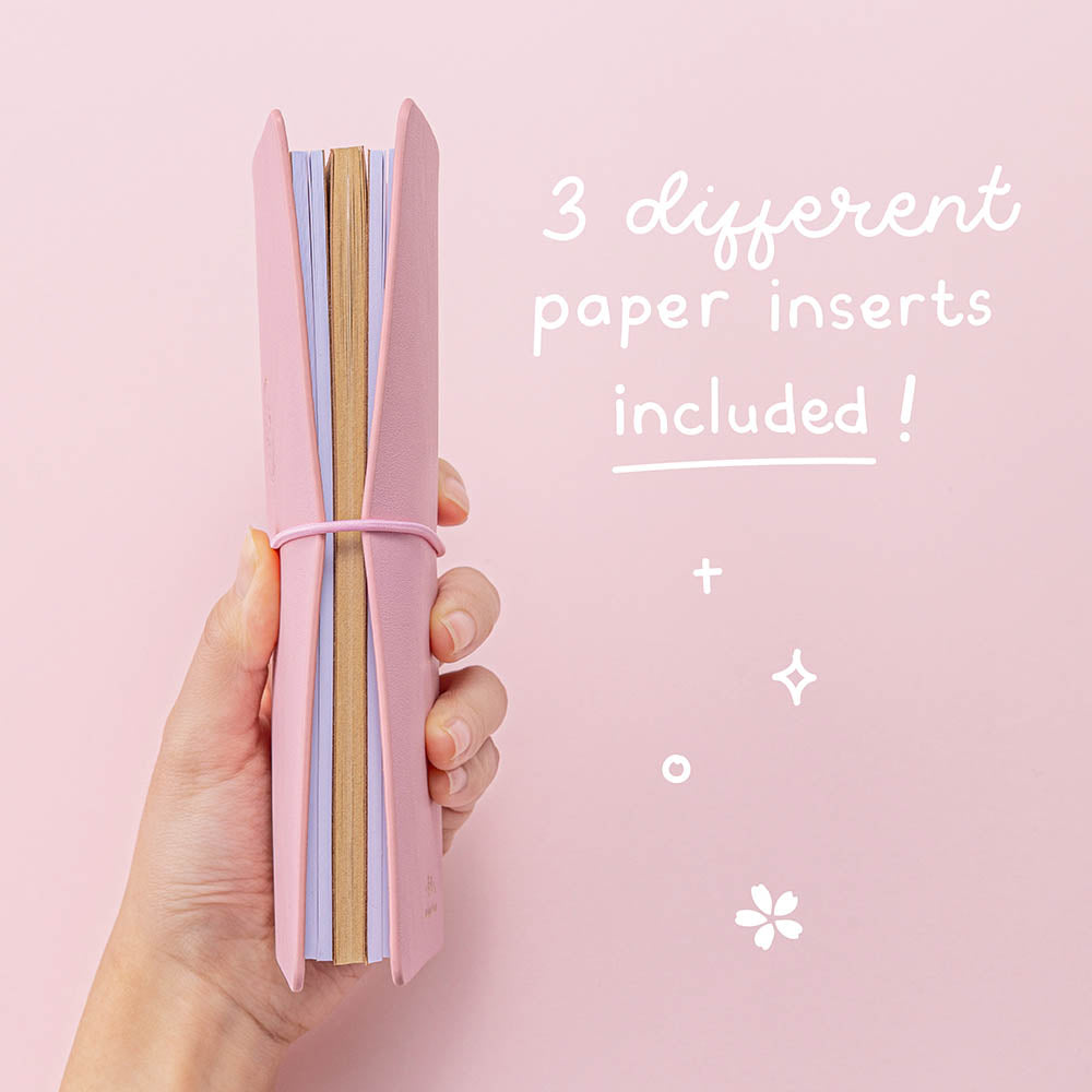 Tsuki ‘Sakura Journey’ Limited Edition Travel Notebook with three different paper inserts held in hand at spine angle in pink background