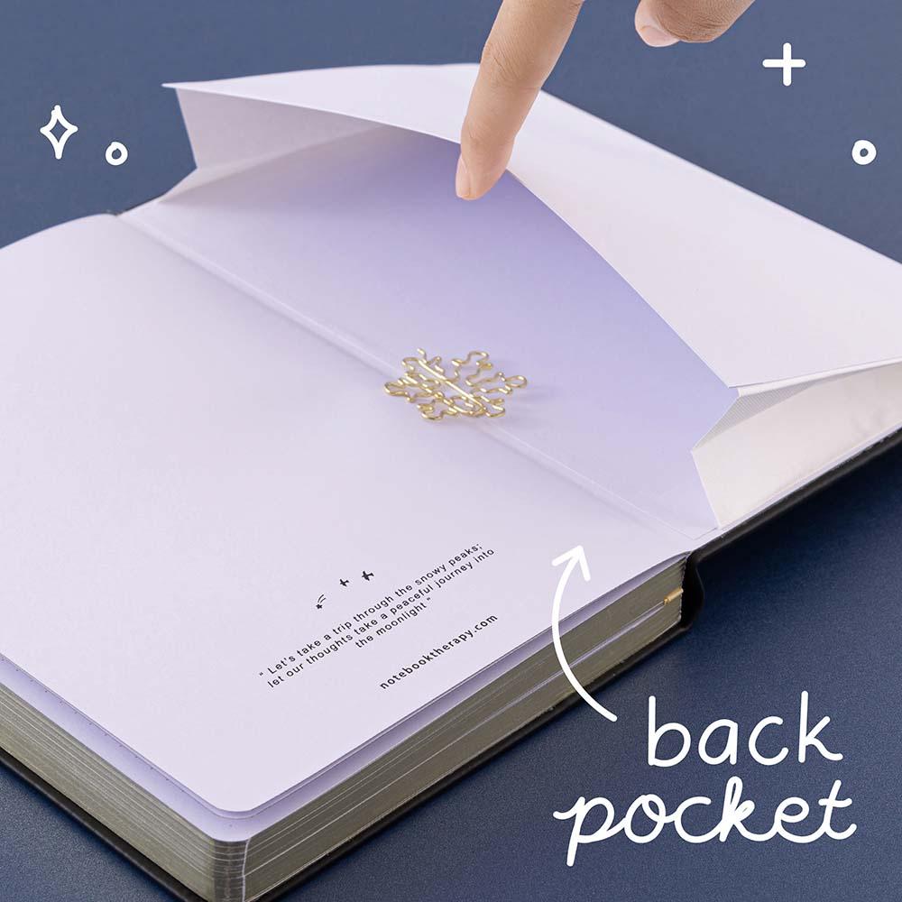 Open back page pocket of Tsuki ‘Winter Journey’ Limited Edition Bullet Journal held in hand with free bookmark gift on navy background