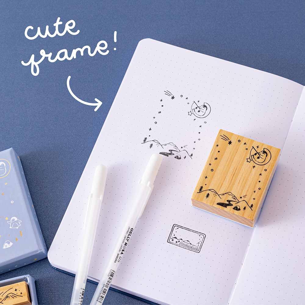 Close up of cute frame stamp from Tsuki ‘Dreams of Snow’ Bullet Journal Stamp Set on open bullet journal page with pens on navy background