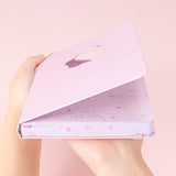 Tsuki Four Seasons: Spring Collector’s Edition 2022 Bullet Journal held in hands at an angle in light pink background