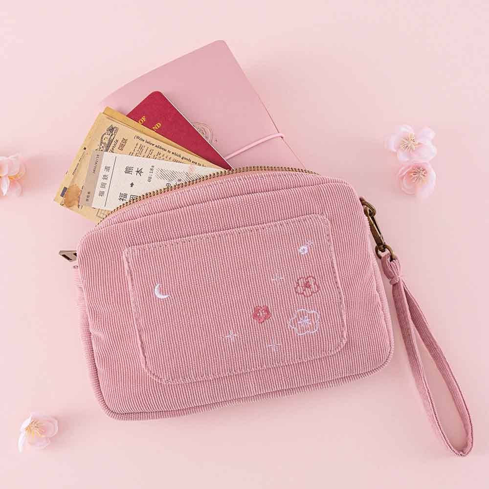Tsuki ‘Sakura Journey’ Travel Pouch with travel essentials and Tsuki ‘Sakura Journey’ Limited Edition Travel Notebook inside with cherry blossoms on pink background