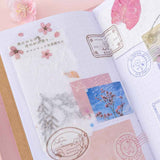 Close up of Tsuki ‘Sakura Journey’ Scrapbooking Set on Tsuki ‘Sakura Journey’ Limited Edition Travel Notebook with cherry blossoms on pink background