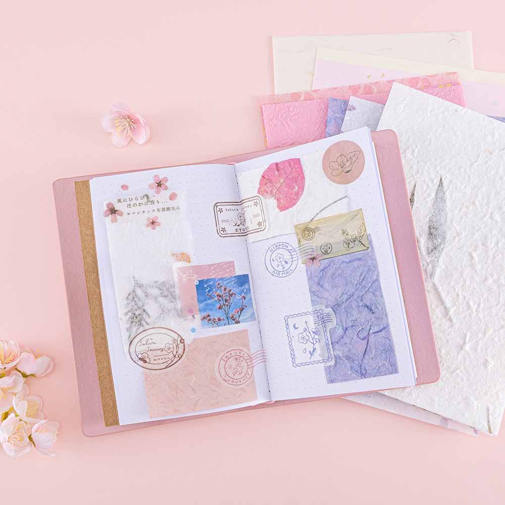 Tsuki ‘Sakura Journey’ Limited Edition Travel Notebook with Tsuki ‘Sakura Journey’ Scrapbooking Set with cherry blossoms on pink background