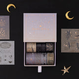 Opened box of Moonlit Alchemy washi tape set revealing 7 washi tapes and 3x sticker sheets on black background