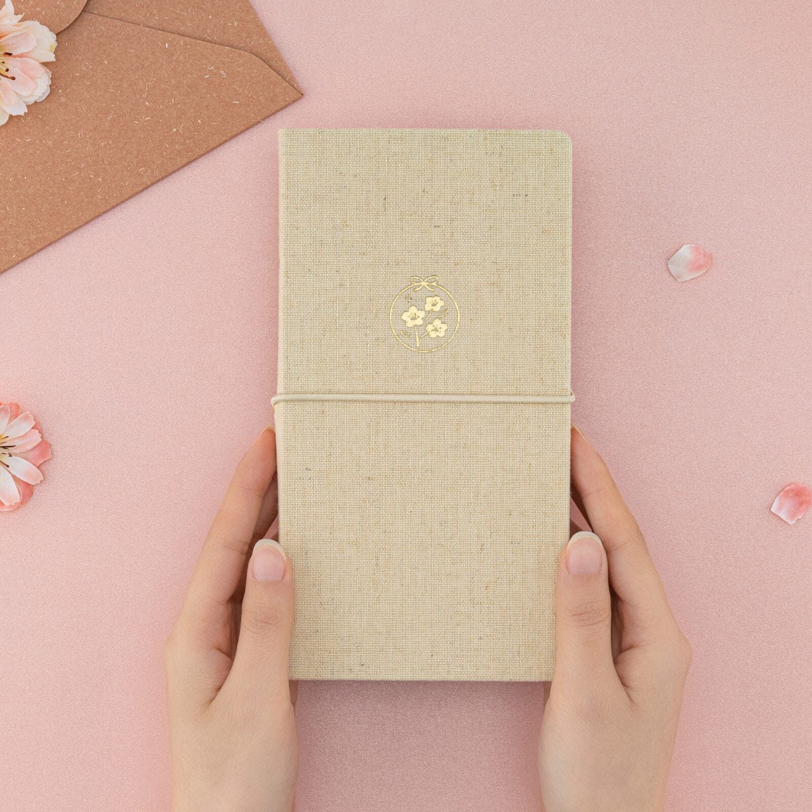 Hands holding Tsuki ‘Sakura Breeze’ Kraft Paper Travel Notebook