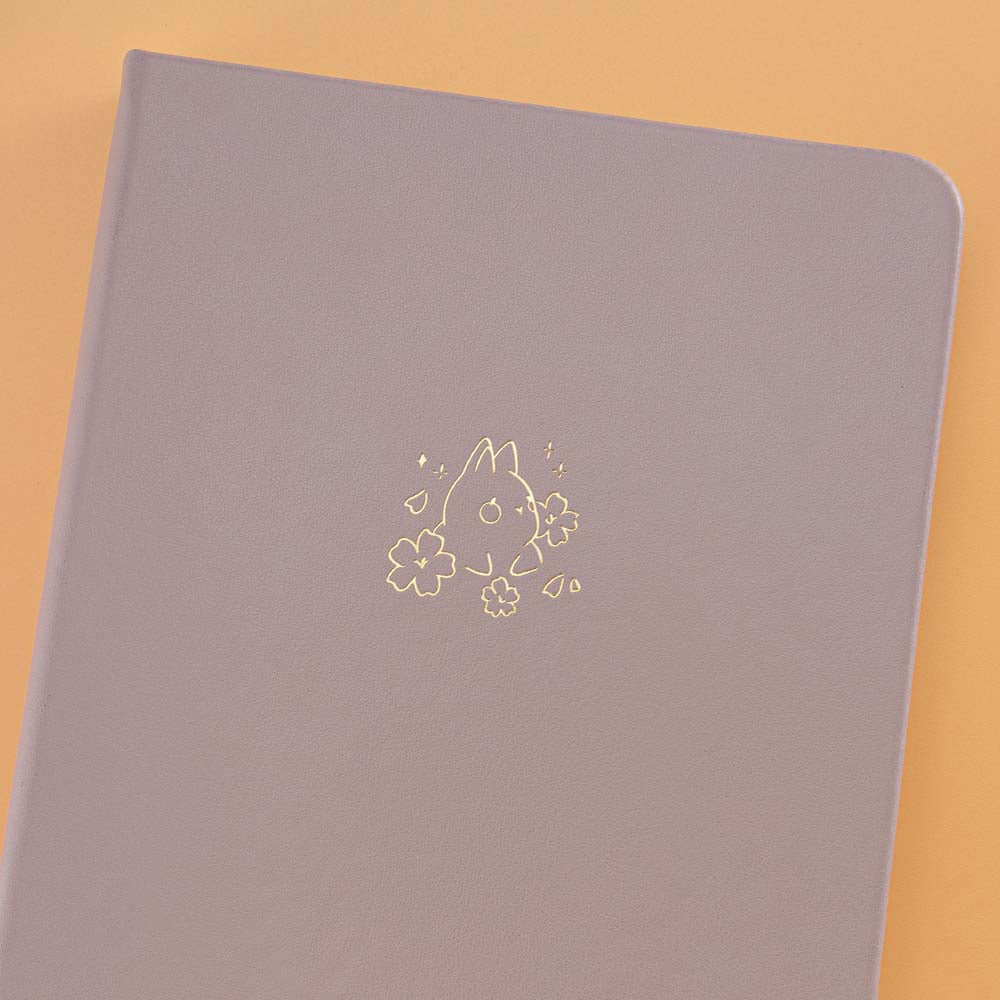 Close up of open front page of Tsuki Blush Pink ‘Bunny Blush’ Limited Edition Bullet Journal designed with Blossom Bujo on apricot background