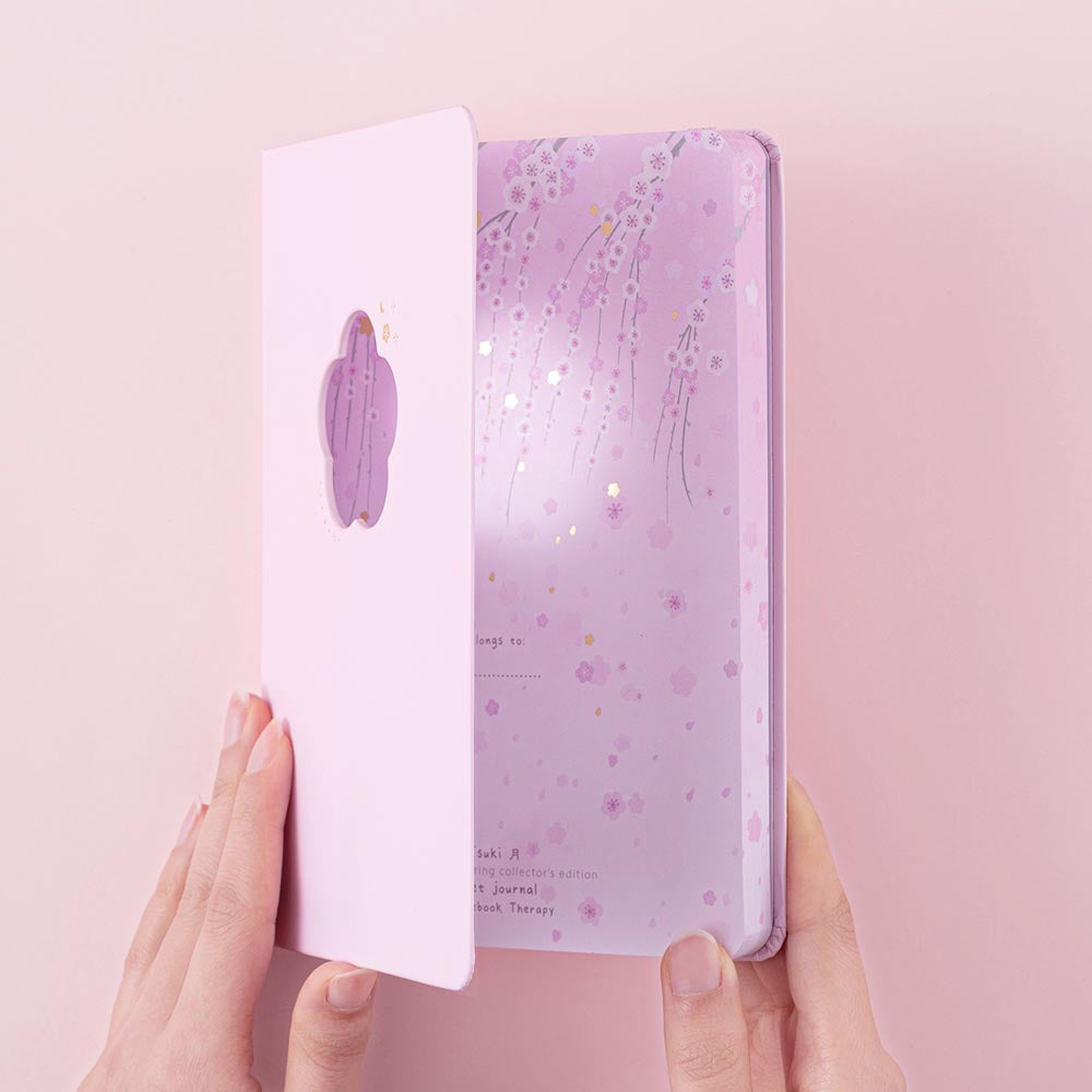 Tsuki Four Seasons: Spring Collector’s Edition 2022 Bullet Journal held in hands on light pink background