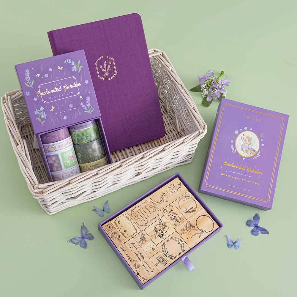 Tsuki ‘Enchanted Garden’ Stamp Set in wicker basket on sage green background with purple flower decoration