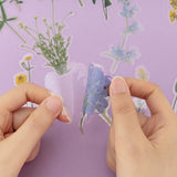 Hand peeling flower sticker off backing paper with pressed flower stickers in the background
