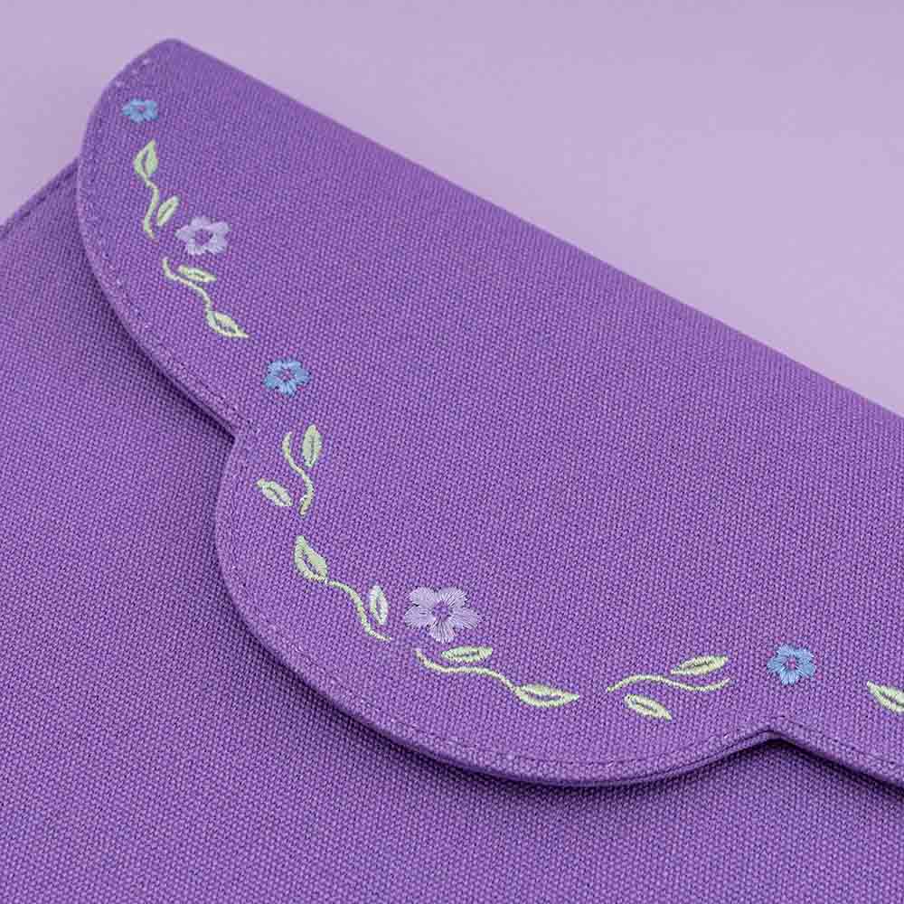 Close up of embroidered details featuring purple and blue flowers and green leaves