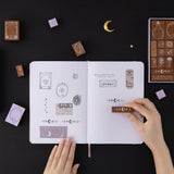 Hand stamping Tsuki ‘Moonlit Alchemy’ stamps on white page bullet journal
