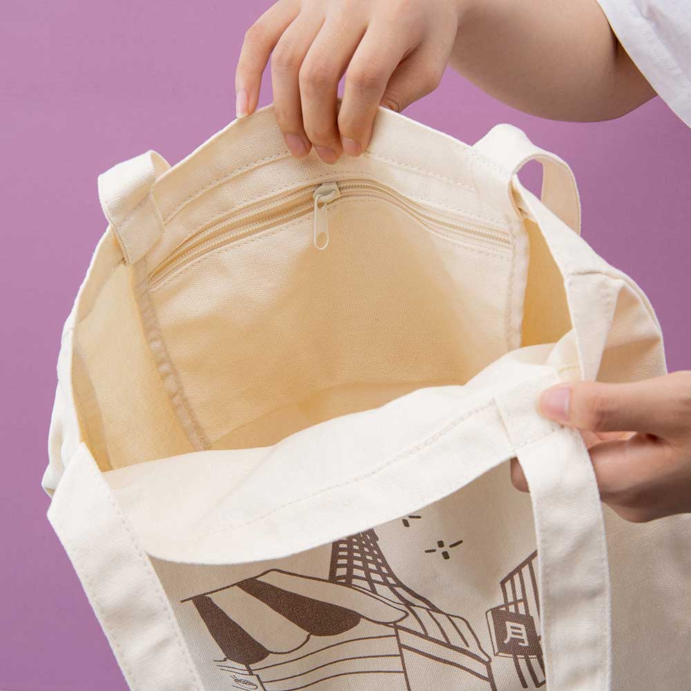 Hands holding up a canvas tote bag showing the inside