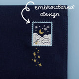 Cloud Dreamland notebook pouch close up on the embroidered stamp design showing a crescent moon above the clouds