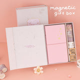 Opened box of Sakura Breeze travel notebook gift set revealing contents including notebook, 4x washi tapes, 2x stamps