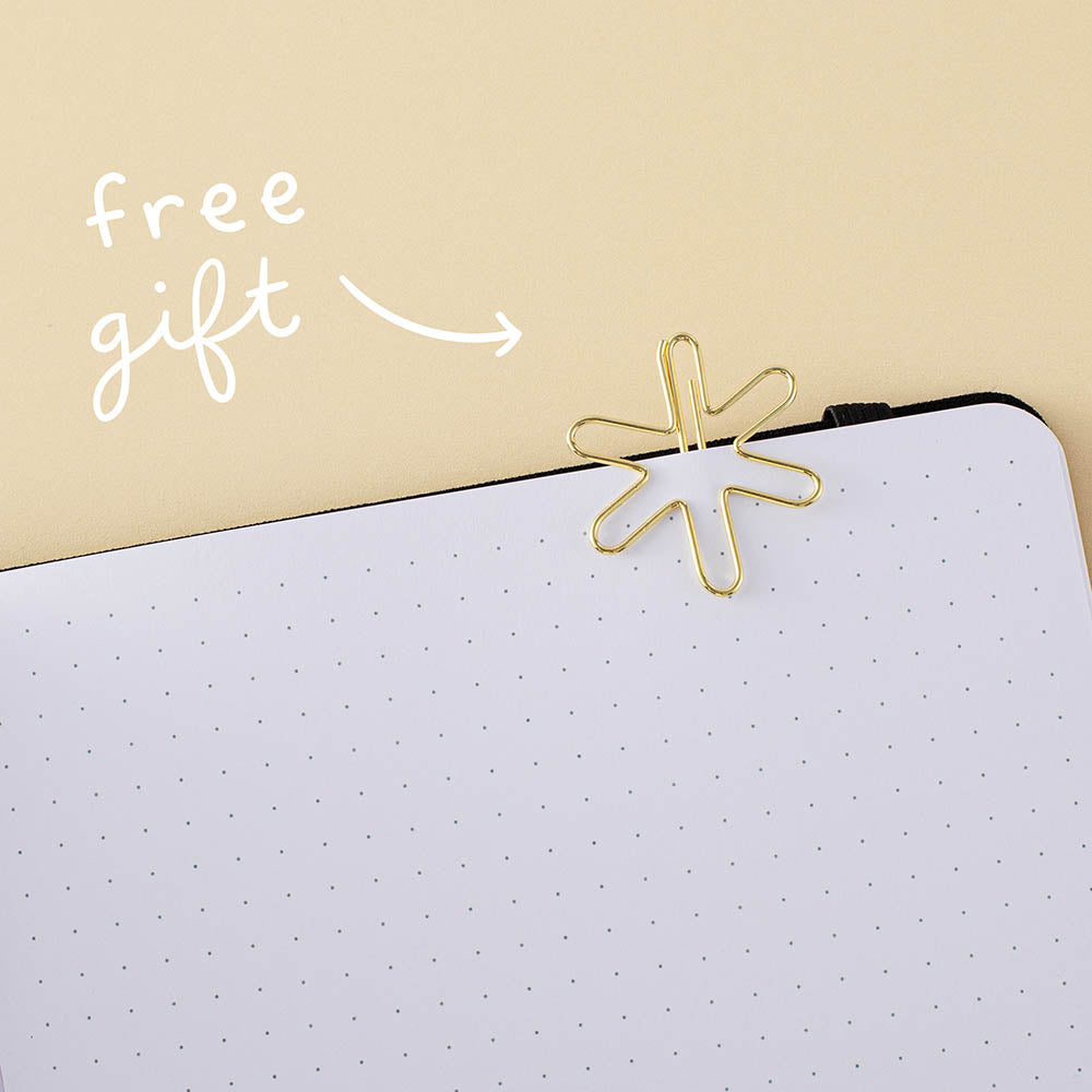 Star-shaped gold paperclip clipped on a bullet journal page with the words “free gift” in white on yellow background