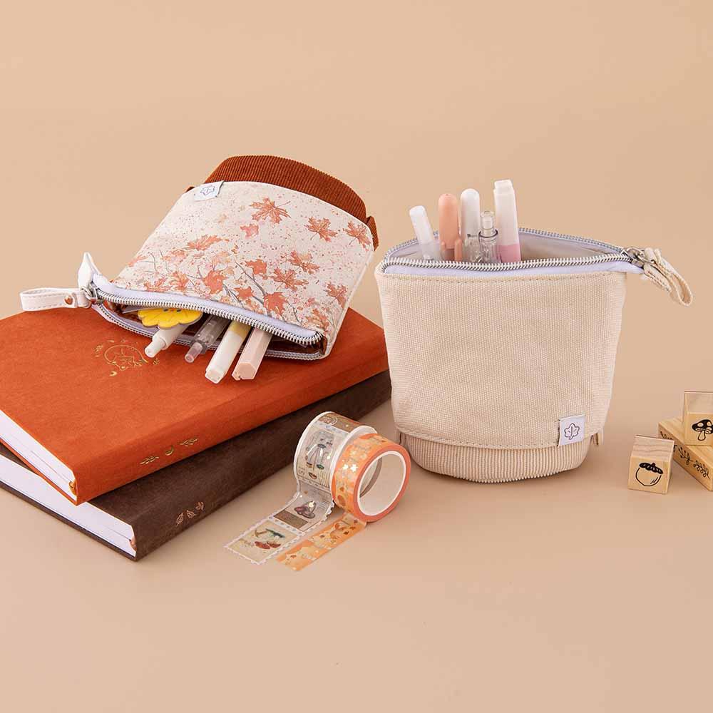 Tsuki ‘Maple Dreams’ Pop-Up Pencil cases in stone and maple with pens inside with Tsuki ‘Kitsune’ Limited Edition Fox Bullet Journal and Tsuki ‘Nara’ Limited Edition notebook with Tsuki ‘Maple Dreams’ Washi Tapes and Tsuki ‘Maple Dreams’ Bullet Journal Stamps on beige background