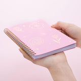 Tsuki sakura pink floral ringbound notebook held in hand at bottom angle in pink background