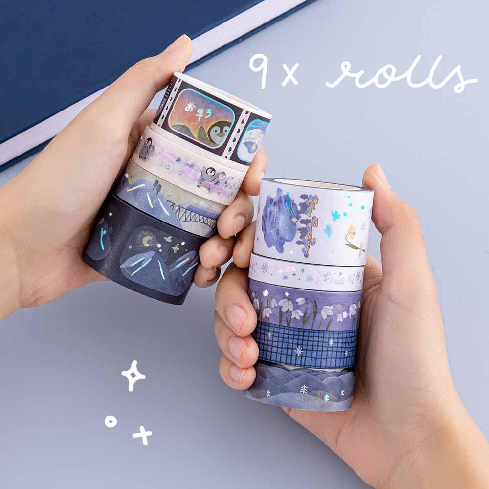 Tsuki ‘Dreams of Snow’ Holographic Washi Tape Set held in hands over Tsuki ‘Winter Wishes’ Limited Edition Bullet Journal on light blue background