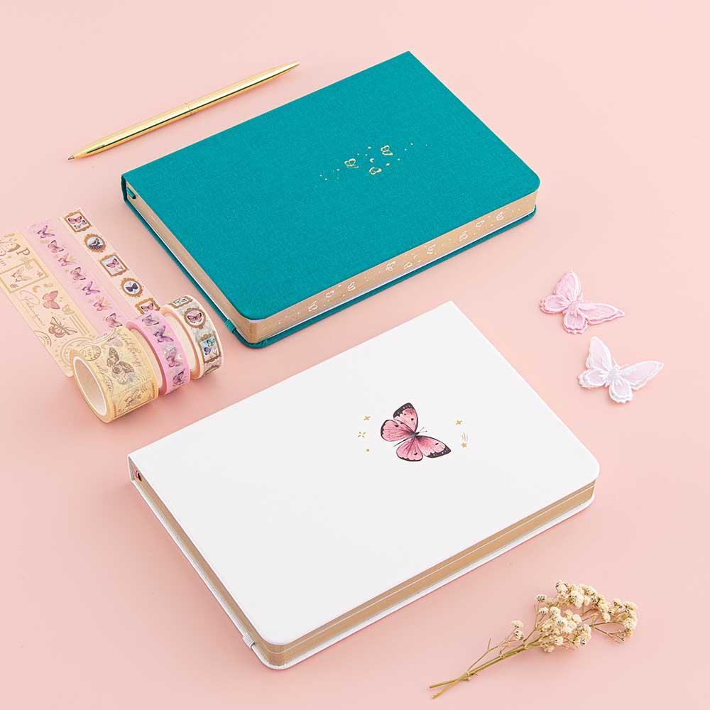 Tsuki Cloud White Sky ‘Flutter + Dream’ Limited Edition Bullet Journal by Notebook Therapy x Pelinkan and Tsuki Teal Sky ‘Flutter + Dream’ Limited Edition Bullet Journal by Notebook Therapy x Pelinkan with Tsuki ‘Flutter + Dream’ Washi Tape Set by Notebook Therapy x Pelinkan with gold pen and butterflies and dried flowers on pastel pink background