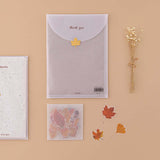 Tsuki Mixed Scrapbook Paper Pack in glassine envelope with free stickers with dried flowers on beige background