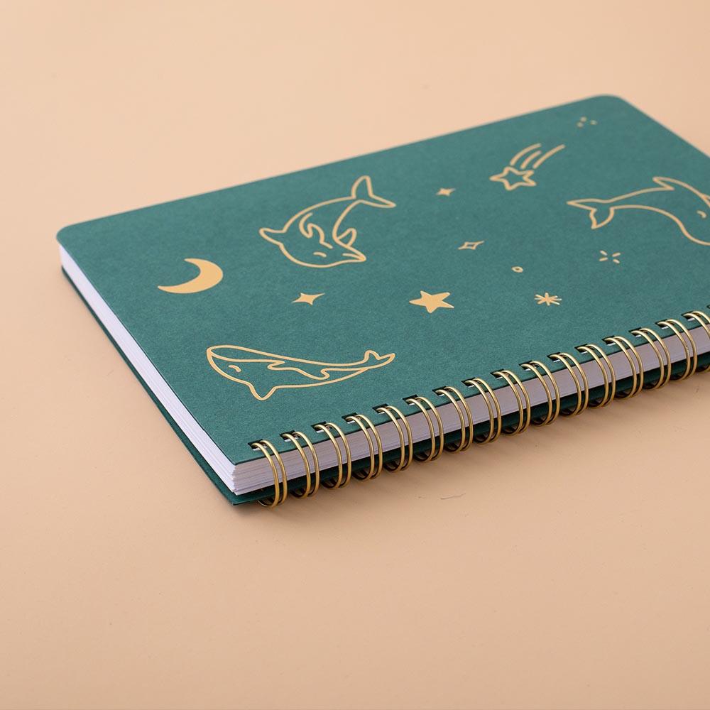 Tsuki Ocean Edition Ring Bound notebook in deep teal at an angle on peach background