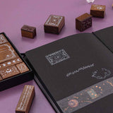 Close up of Tsuki ‘Moonlit Spells’ Bullet Journal Stamp Set on open black page bullet journal with Tsuki ‘Moonlit Blush’ Washi Tape on purple background