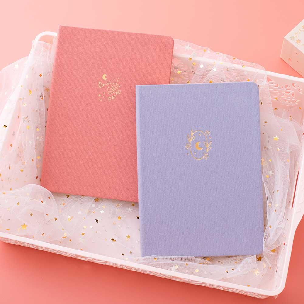 Tsuki ‘Full Bloom’ Limited Edition Bullet Journal with Tsuki ‘Suzume’ Limited Edition Notebook with netting in basket on coral pink background