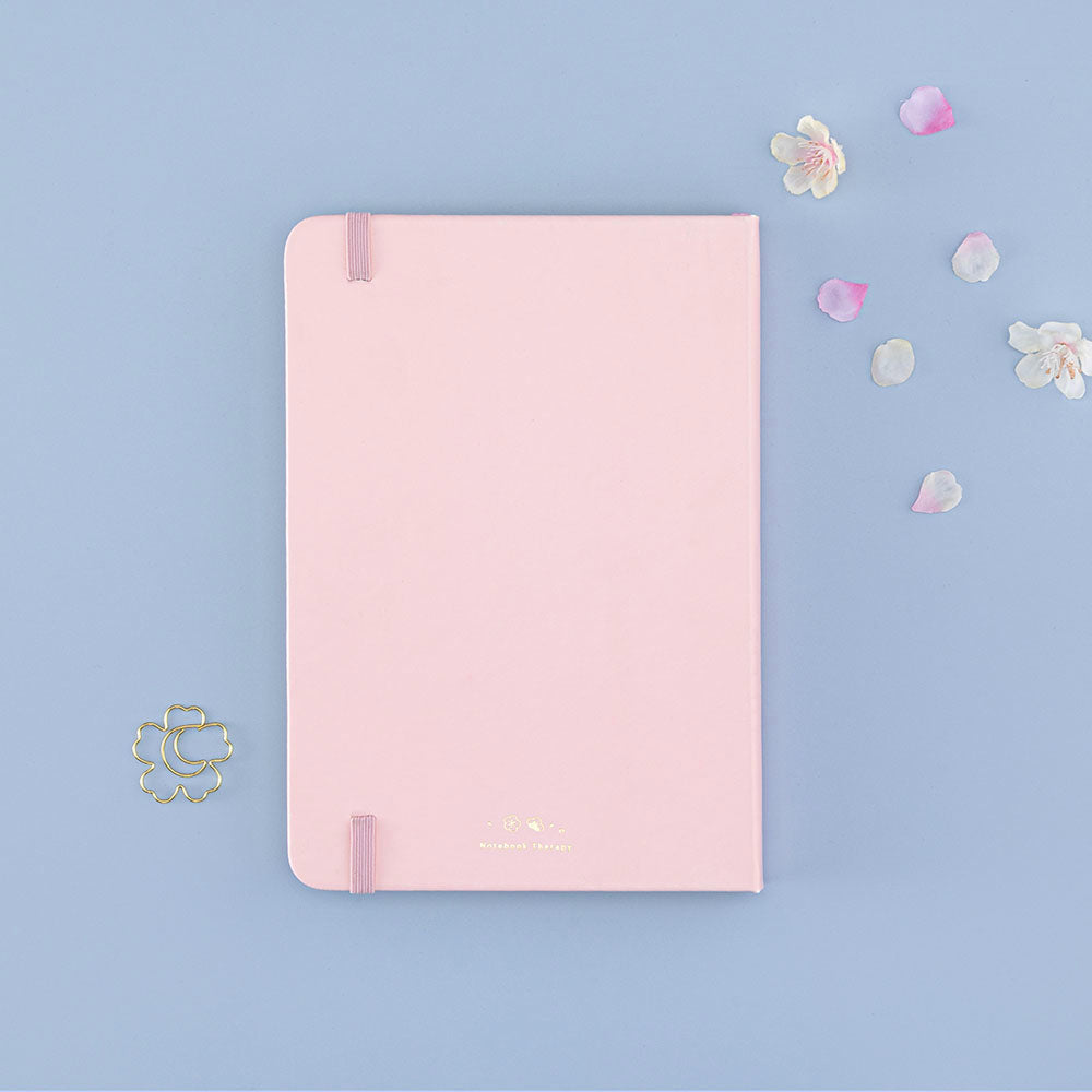 Back cover of Tsuki ‘Lunar Blossom’ Limited Edition Bullet Journal with free bookmark gift with cherry blossom petals on light blue background