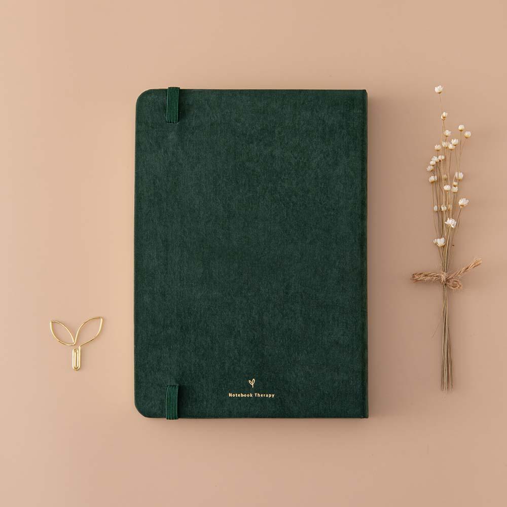 Back cover of Tsuki ‘Midnight Garden’ Limited Edition Bullet Journal with free paperclip gift and dried flowers on beige background