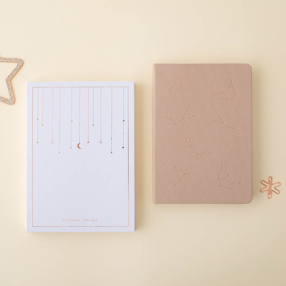 Flatlay of beige constellations bullet journal with the tsuki gift box and the rose gold star paperclip
