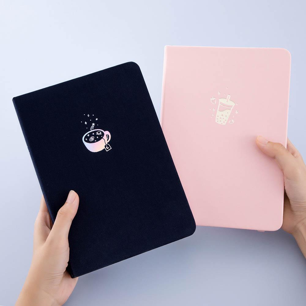 Tsuki ‘Cup of Galaxy’ Limited Edition Holographic Bullet Journal with Tsuki ‘Ichigo’ Limited Edition Boba notebook held in hands in light blue background