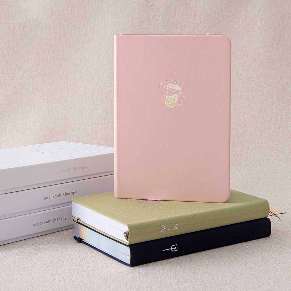 Tsuki ‘Ichigo’ Limited Edition Boba Bullet Journal and Tsuki ‘Cup of Galaxy’ Limited Edition Holographic notebook and Tsuki ‘Matcha Matcha’ Limited Edition Bullet Journal on beige linen covered table