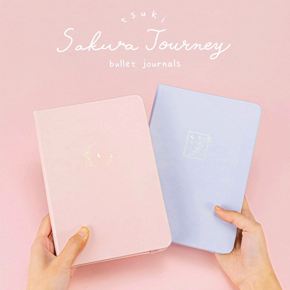 Tsuki ‘Sakura Journey’ Limited Edition Bullet Journal with Tsuki ‘Lunar Blossom’ Limited Edition Bullet Journal held in hands in pink background