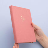 Tsuki ‘Suzume’ Limited Edition Bullet Journal held in hands in lilac background