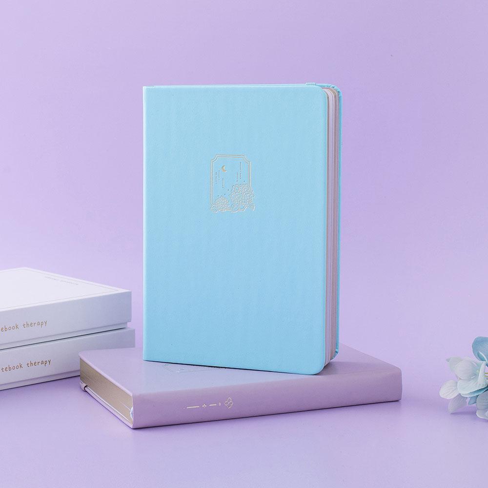 Tsuki Endless Summer Limited Edition Bullet Journals in Lilac Bloom and Petal Blue with eco-friendly gift box packaging and light blue hydrangea flowers in lilac background