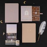 Flatlay of Moonlit Alchemy collection including washi tapes, stamp set, Moonlit Dusk and Stardust Dawn bullet journals