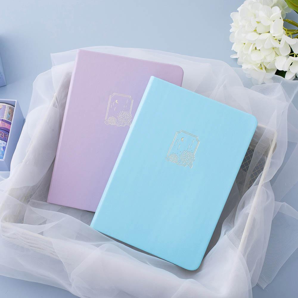 Tsuki Endless Summer Limited Edition Bullet Journals in Lilac Bloom and Petal Blue in basket with netting on light blue background